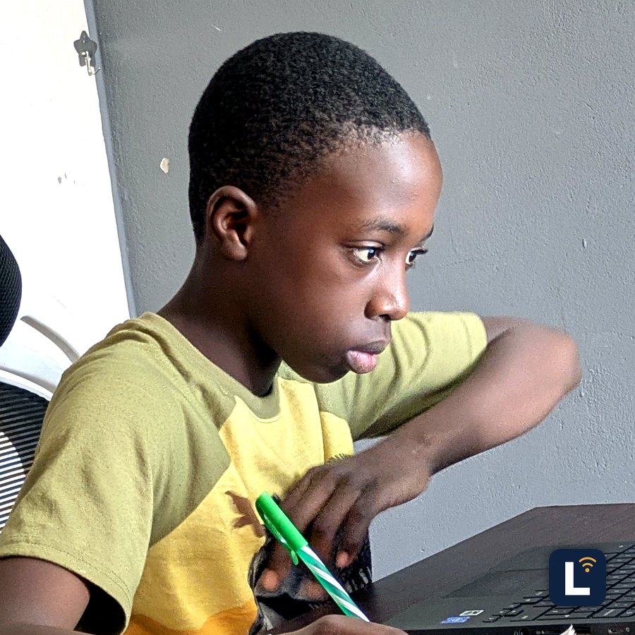 A Lory Online School student writing in a notebook next to a laptop